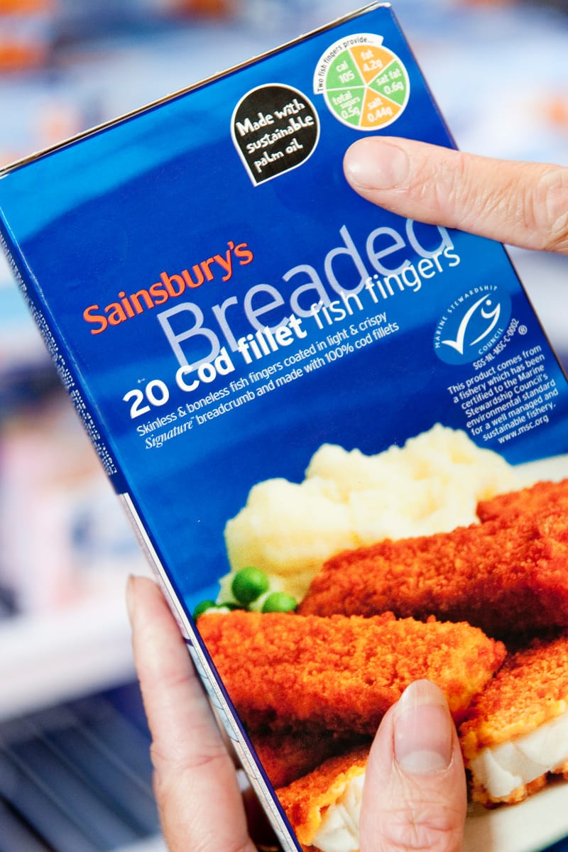 A mother reading an ingredients label looking to buy Marine Stewardship Council (MSC) approved breaded fish that is also made with sustainably produced palm oil